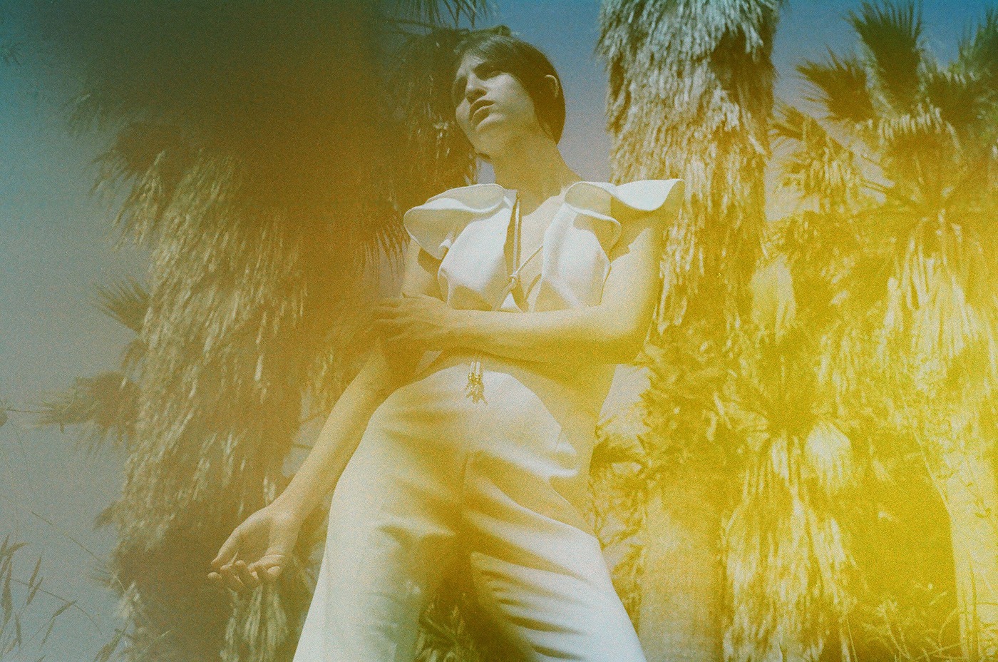 Beautiful girl in a white suit among the palm trees. Shooting on expired film with broken camera.