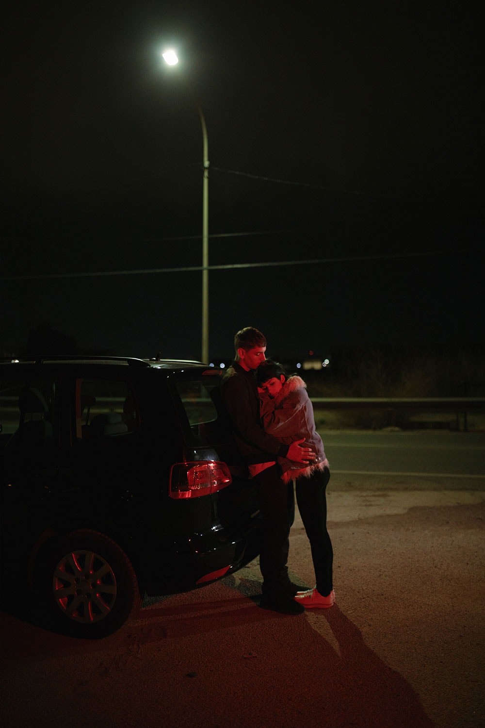 Embracing Couple Near Car On Dark Road