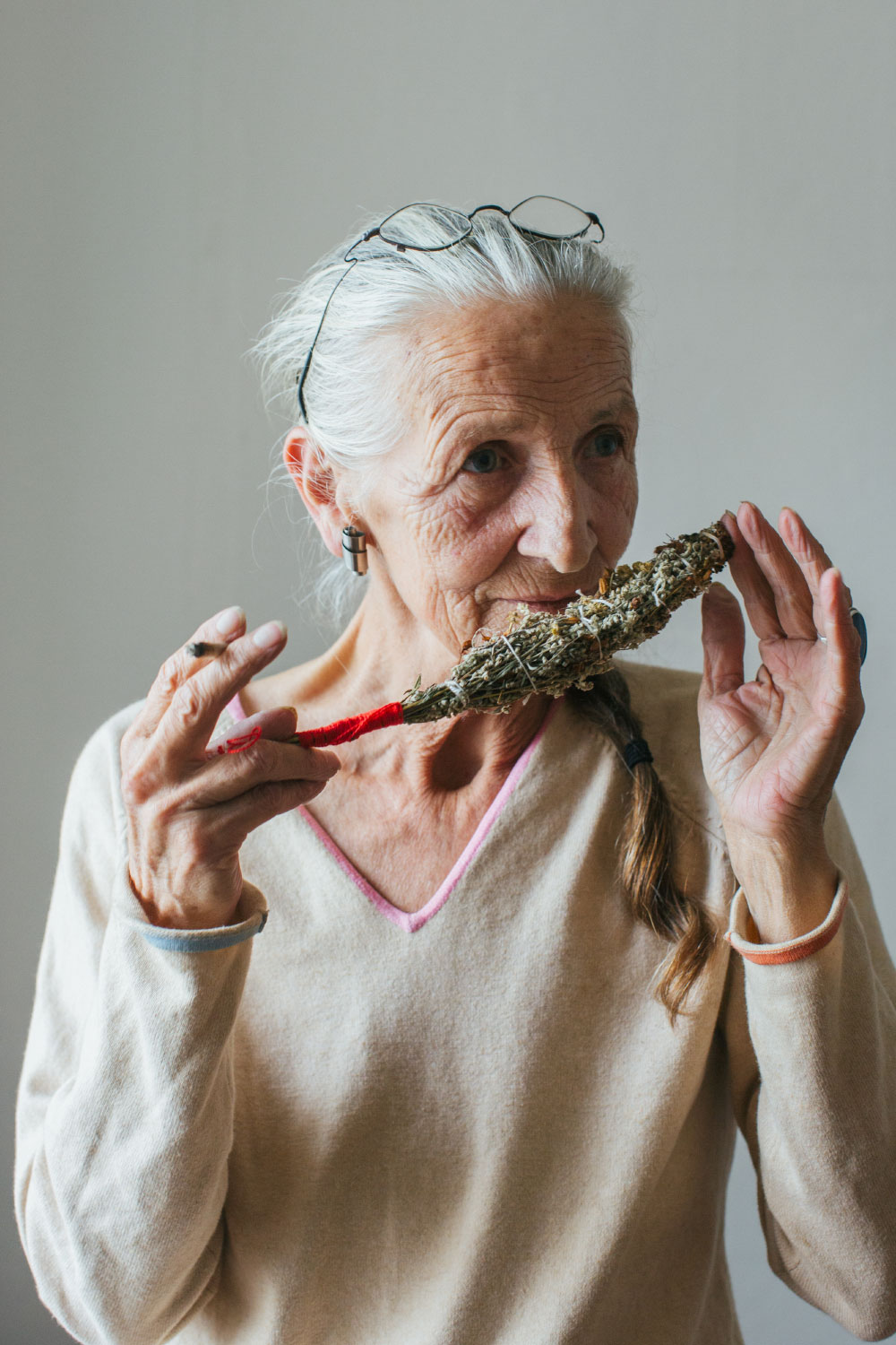 Indoor Portrait Of Senior Smoking Woman With Grey Hair Smelling Self-Made Smudge Stick