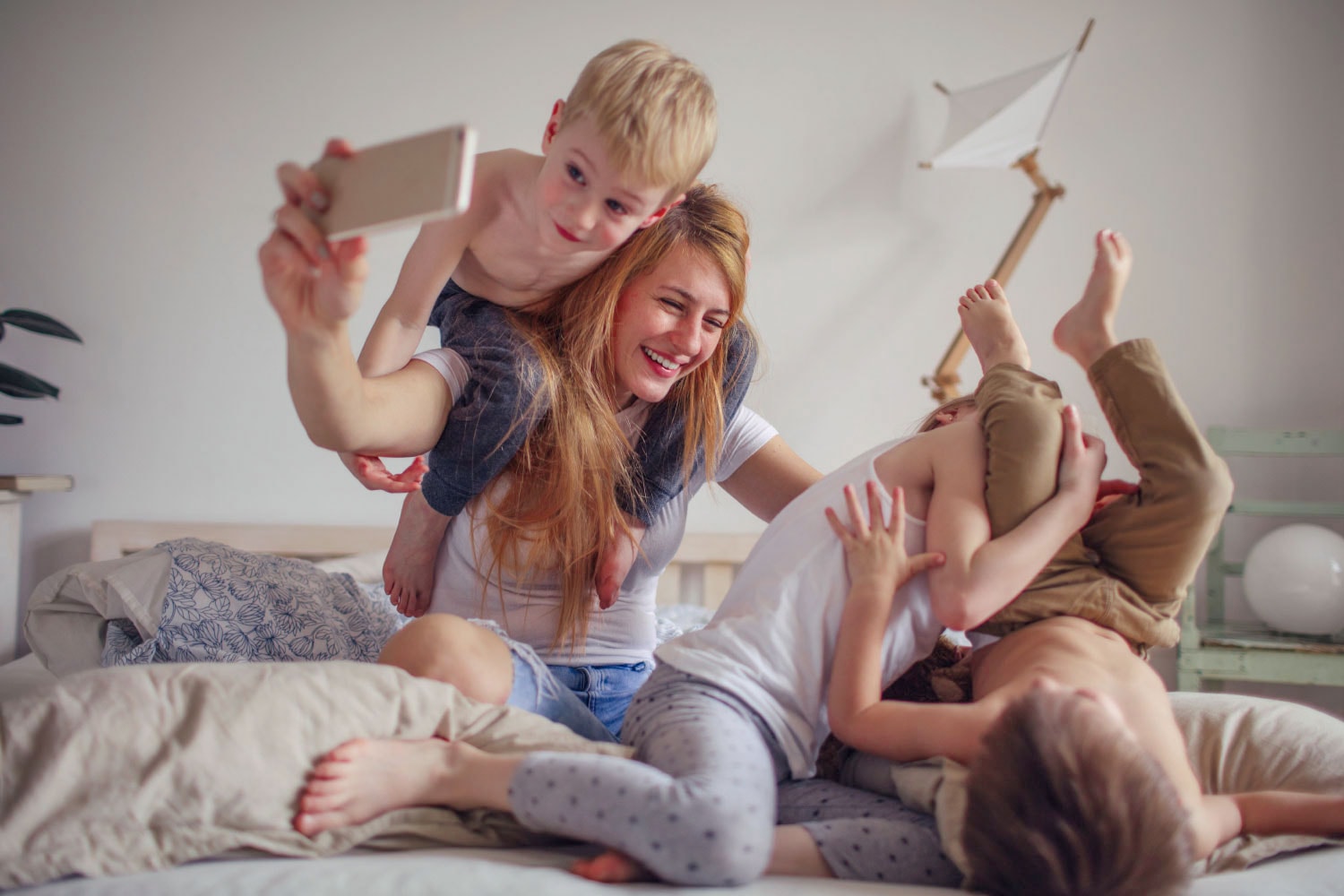 Everyday Joy. Woman and her children spending time together in the bedroom
