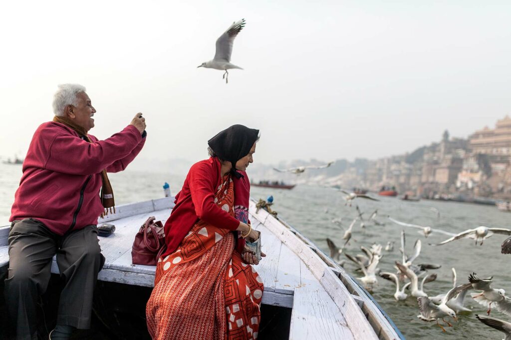 Active Seniors Traveling In A Boat And Taking Photographs Of Flying Birds In Varanasi,India