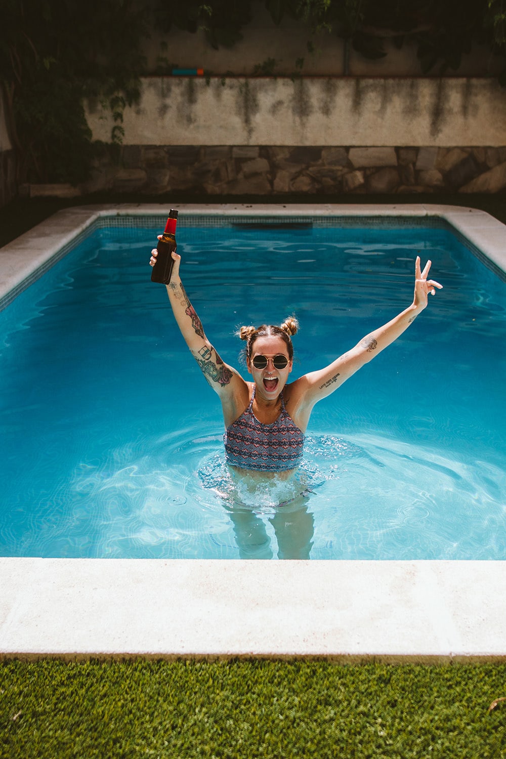 Portrait of woman with sunglasses drinking a beer inside the pool Woman Drinking A Beer In The Pool