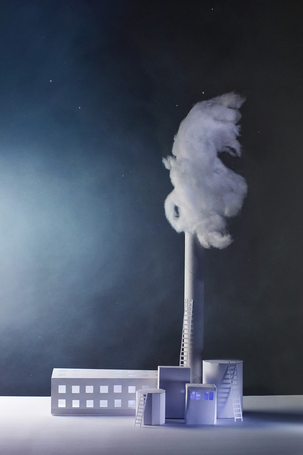 A paper factory at night with plumes of smoke rising from its single chimney