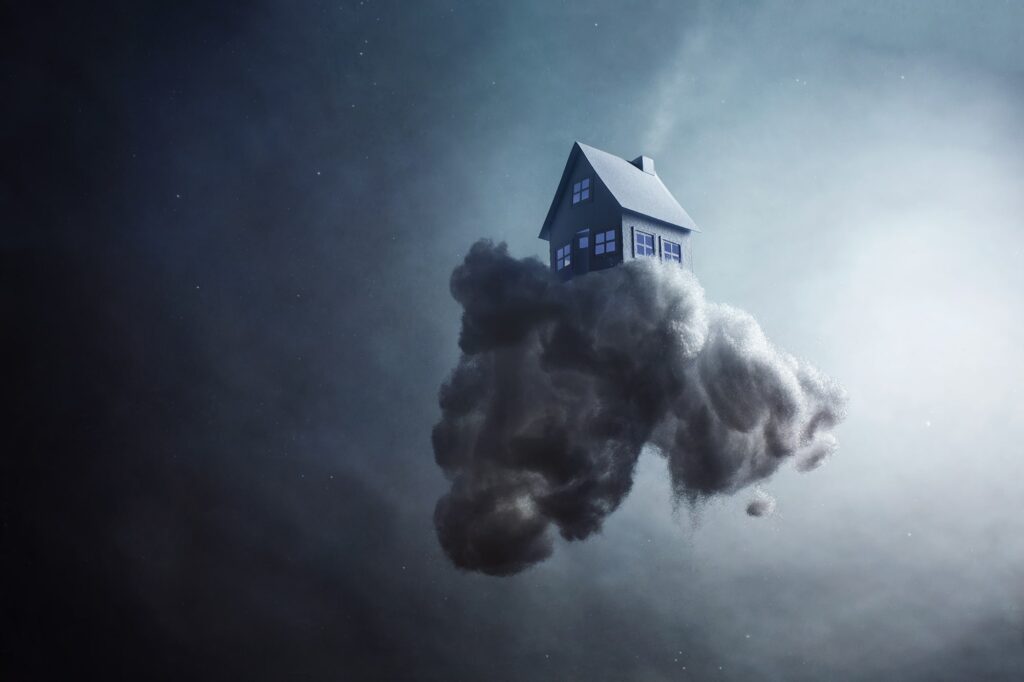A paper house sits on top of a dark cloud floating in a dramatic sky. For many in our society a home of their own has become nothing more than a dream.