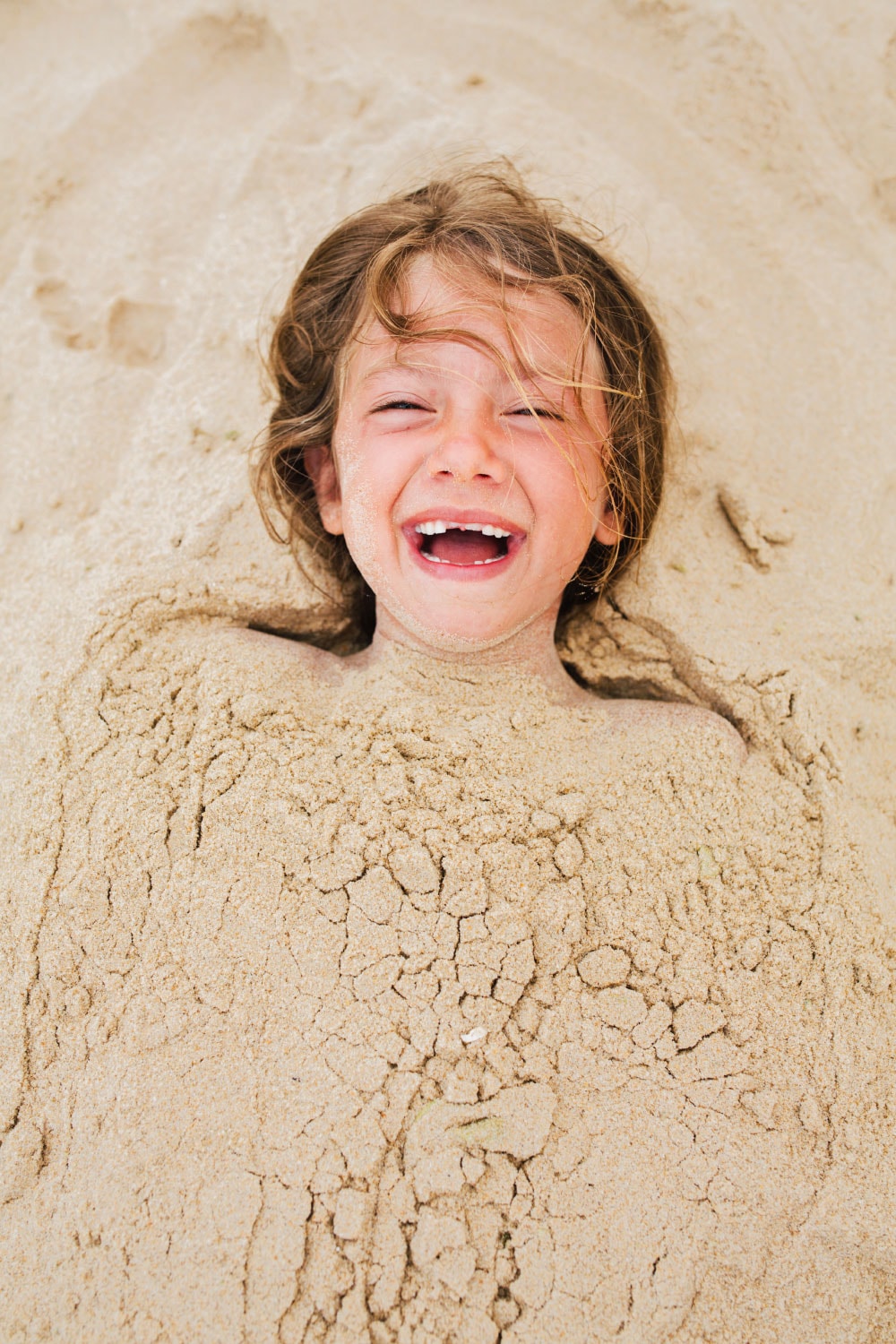 Copy space and a child lying buried in the sand just for fun and enjoyment on the beach