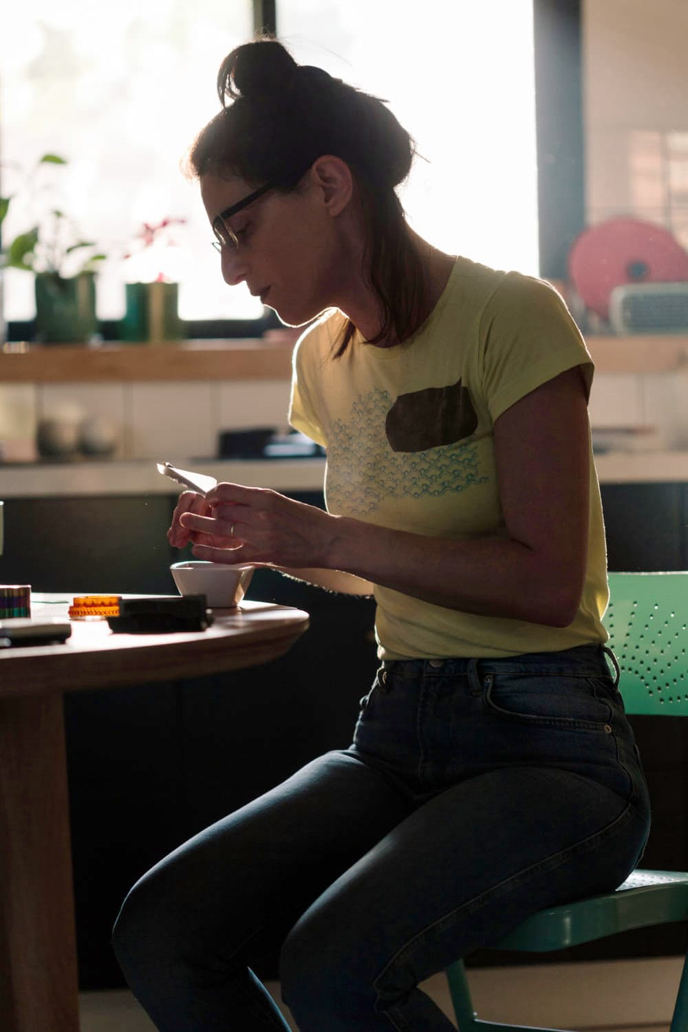 Adult woman sitting at her dining table at home, making a cannabis cigarette.