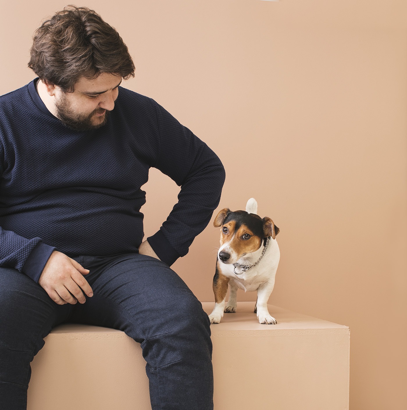Studio prortrait of plus size young man with beard looking at cute dog.