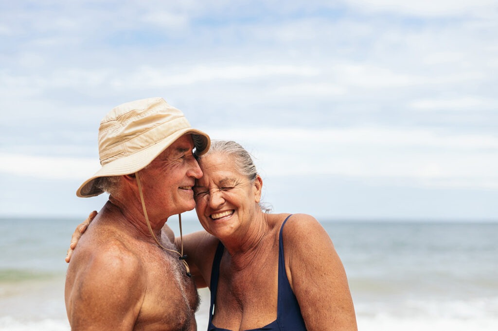 Portrait of smiling elderly couple in swimsuits in front of the sea