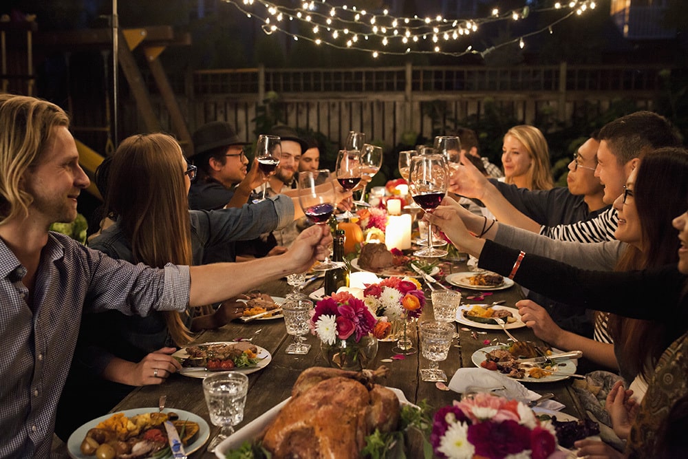 Friends enjoying dinner outside, raising their glass for a toast.