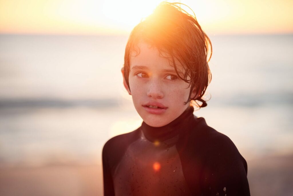 Boy With A Sad Expression At The Beach At Sunset