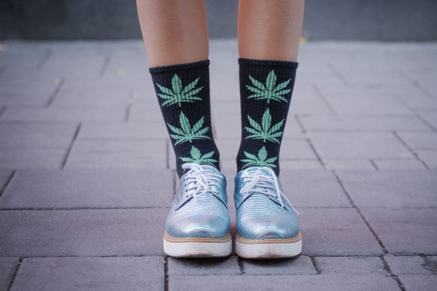 Close up shot of an anonymous female's shoes and socks with marijuana print on it
