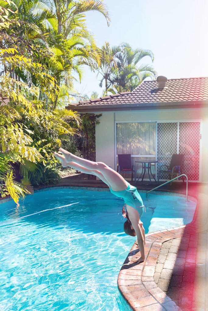 girl doing a handstand into the pool