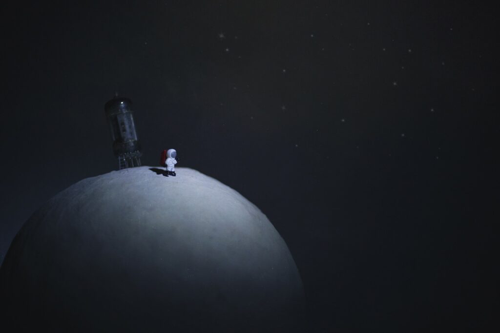 All Alone In A Big Universe... A tiny astronaut stands alone on a Paper Mache planet looking out at a strange galaxy.