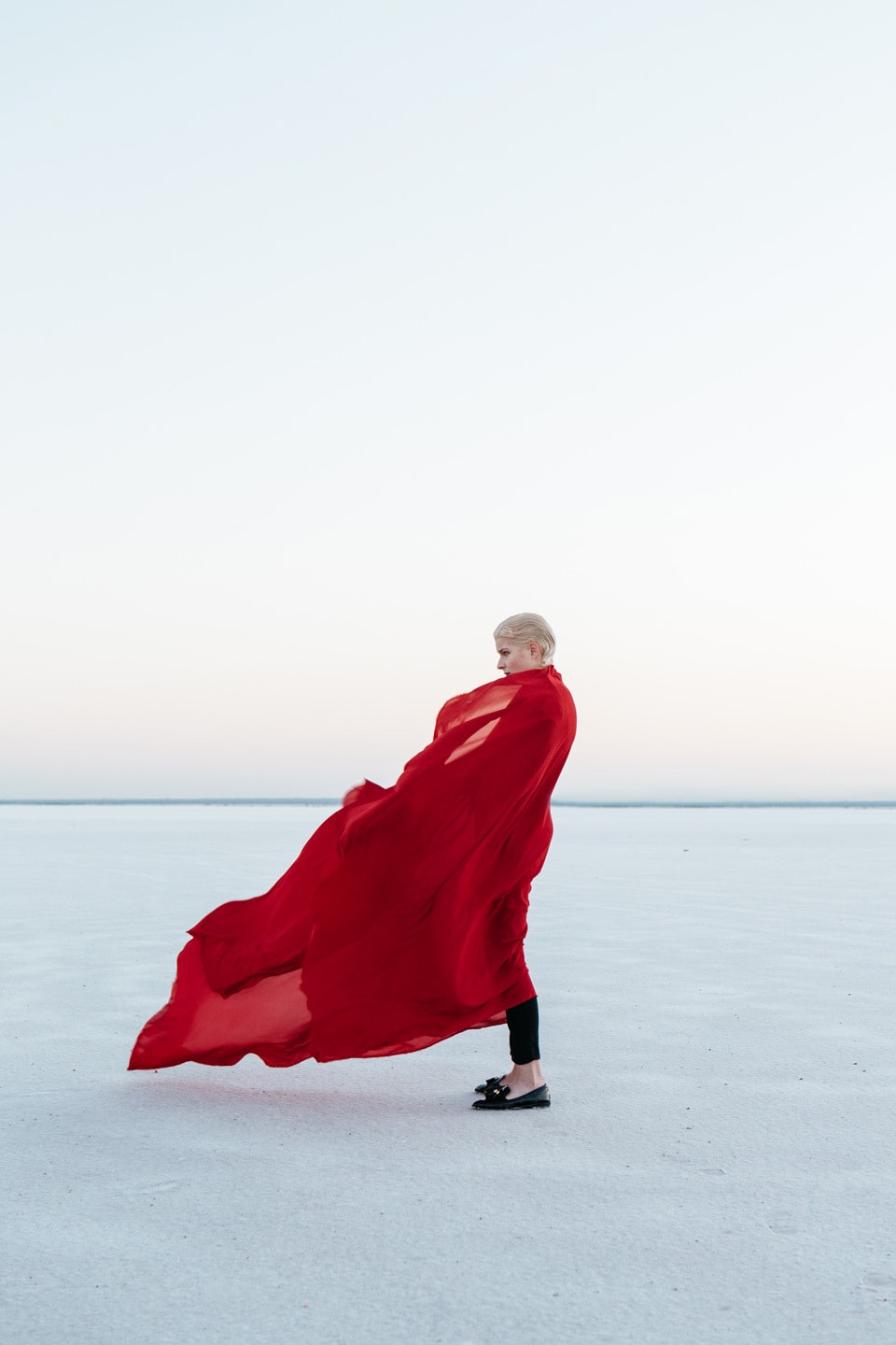 Woman Standing salt flats with fabric wrapped around her and blowing in the wind