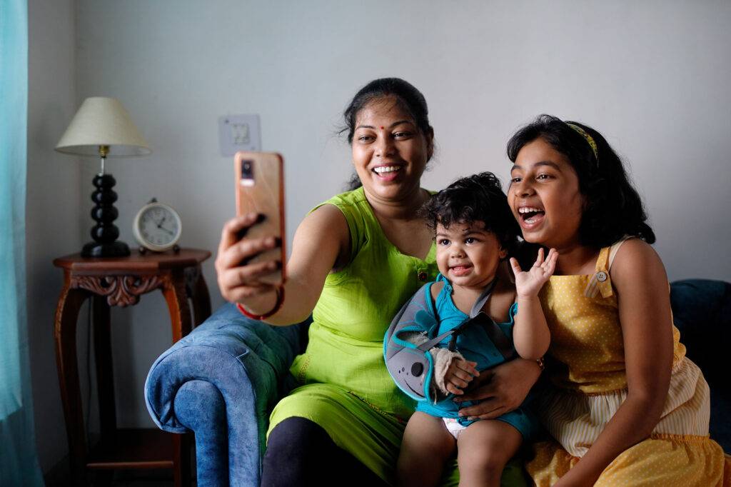 Mother taking selfie with her two daughters,smiling and having fun indoors