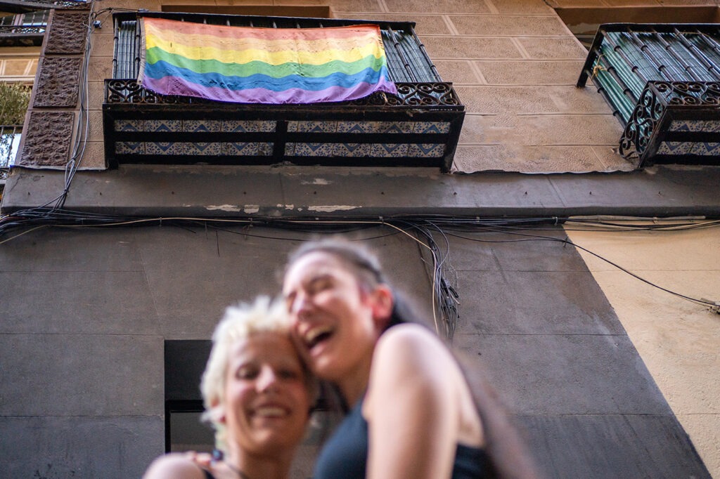 Lesbian Girls In Front Of LGBT Flag On A Balcony.