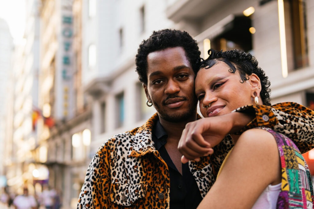 Stock photo of an amazing cool black non-binary couple hugging in the city of Madrid.