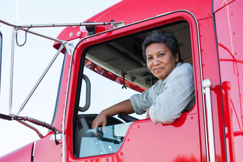Hispanic female truck driver with her Kenworth Class 8 commercial truck