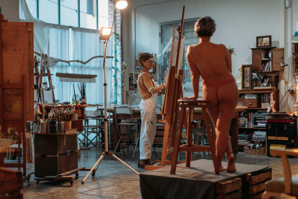 Woman painting model on canvas at her studio