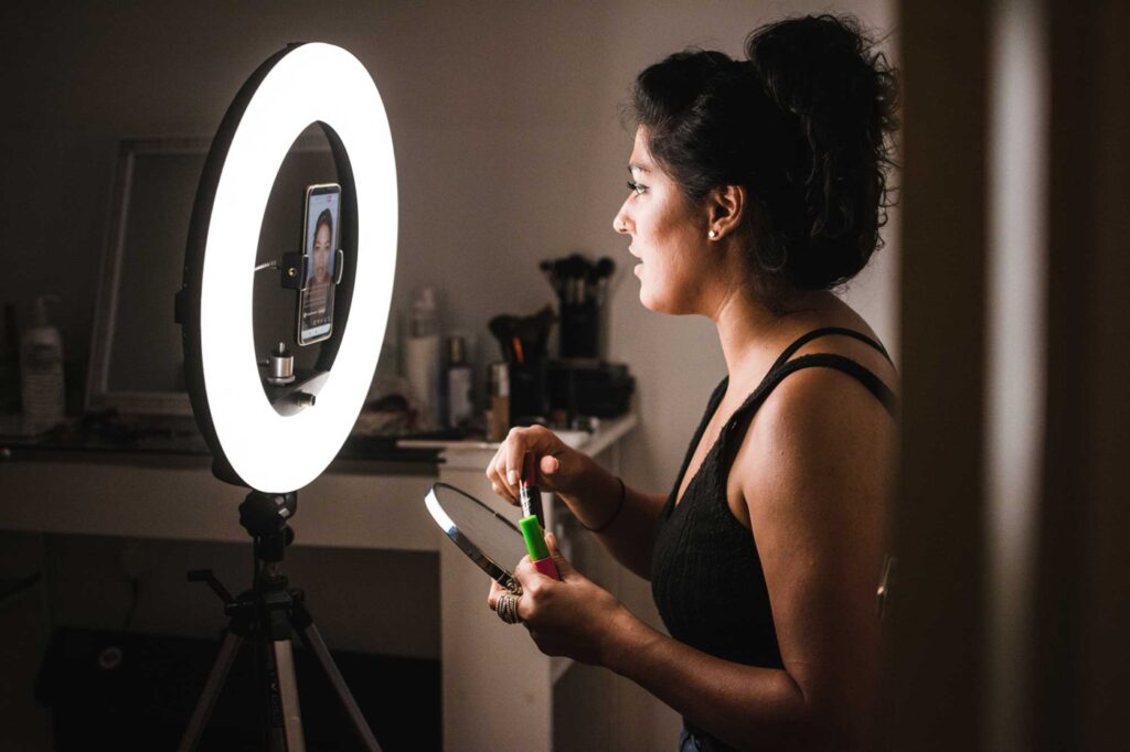 Beautiful and confident latin woman at home teaching a make up technique class in a live stream from a social media app.