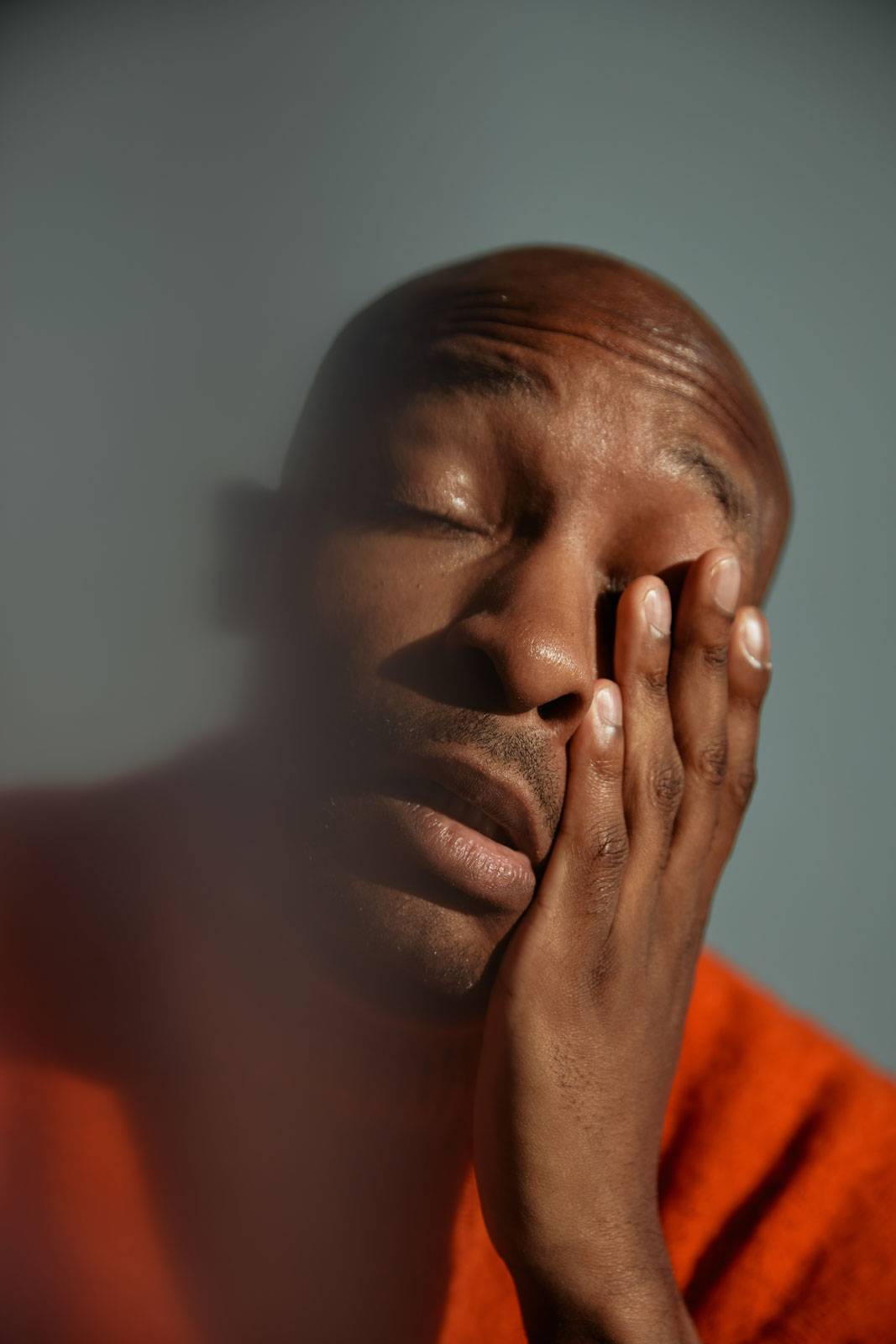 Young African American man in red sweater with his hand on his face with an exhausted gesture