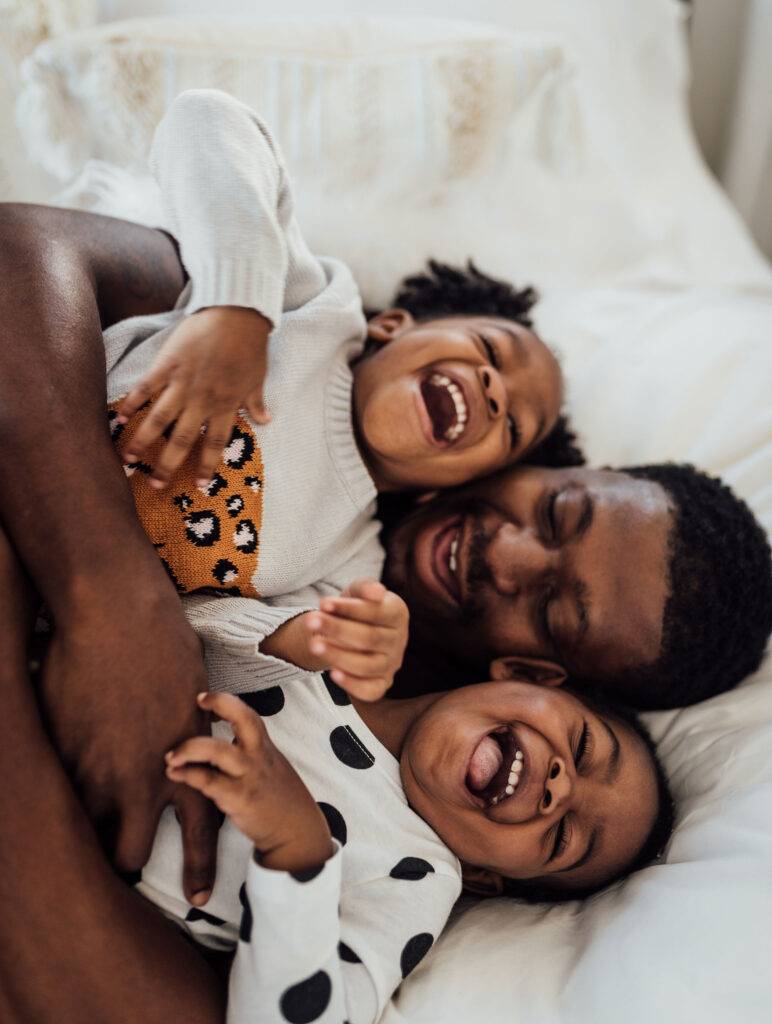 Dad Playing With His Daughters In Bed Laughing And Smiling