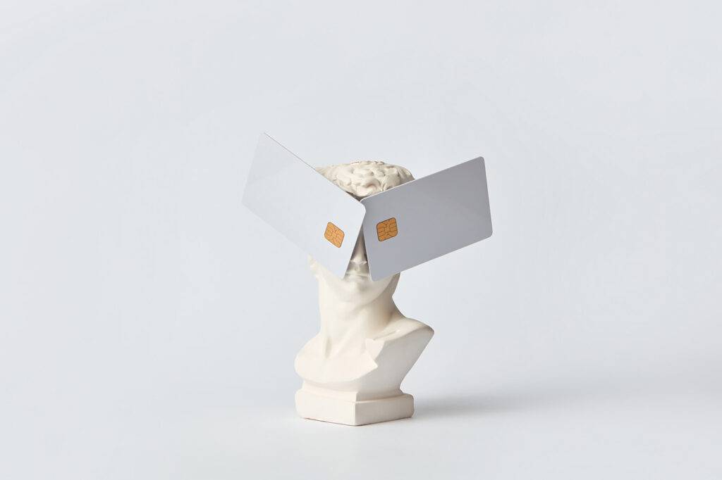 Funny white David statue with credit cards covering eyes on white background with copy space