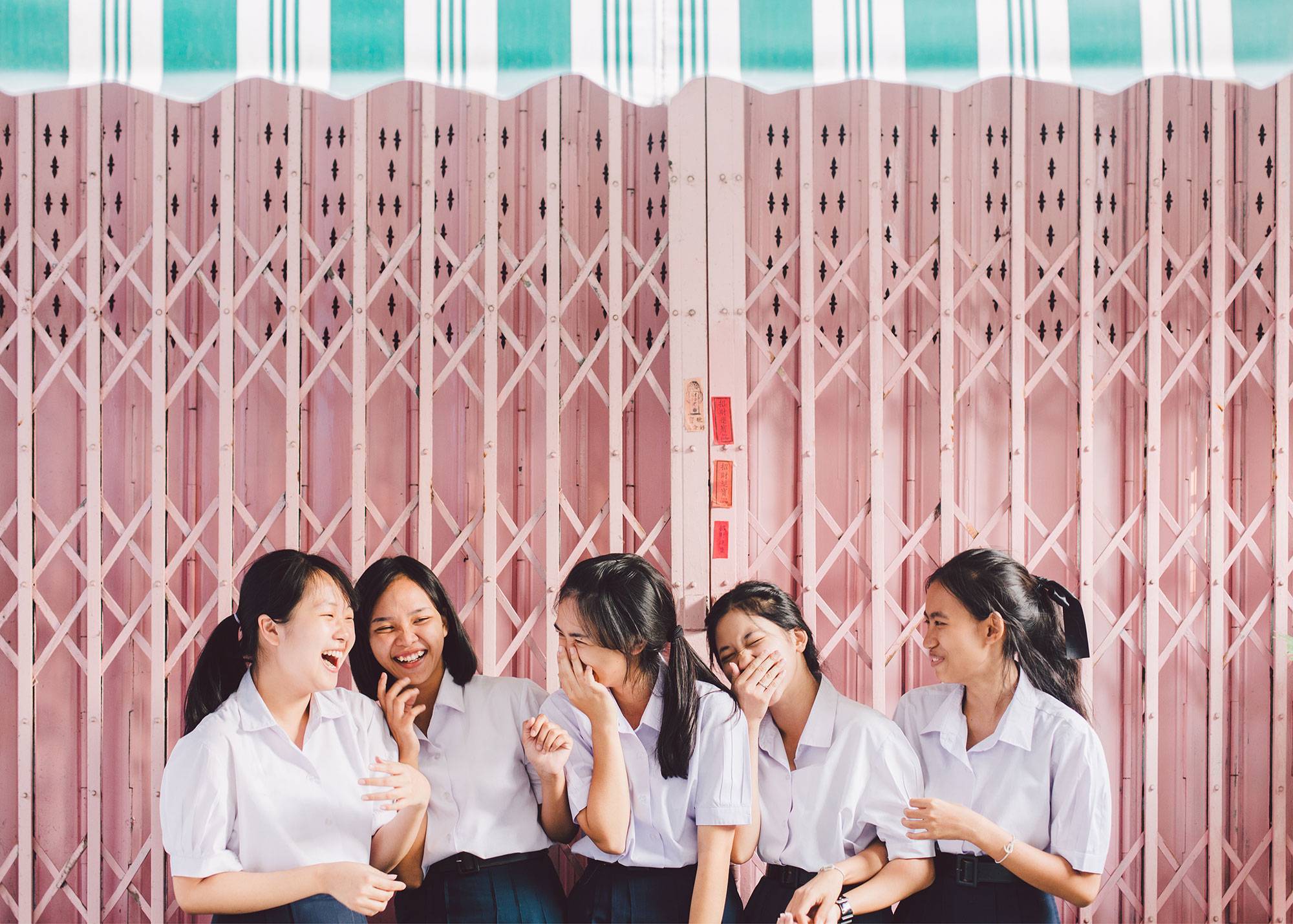 Asian High School Girls Standing In Front Of Pastel Pink Garage Door In Thailand