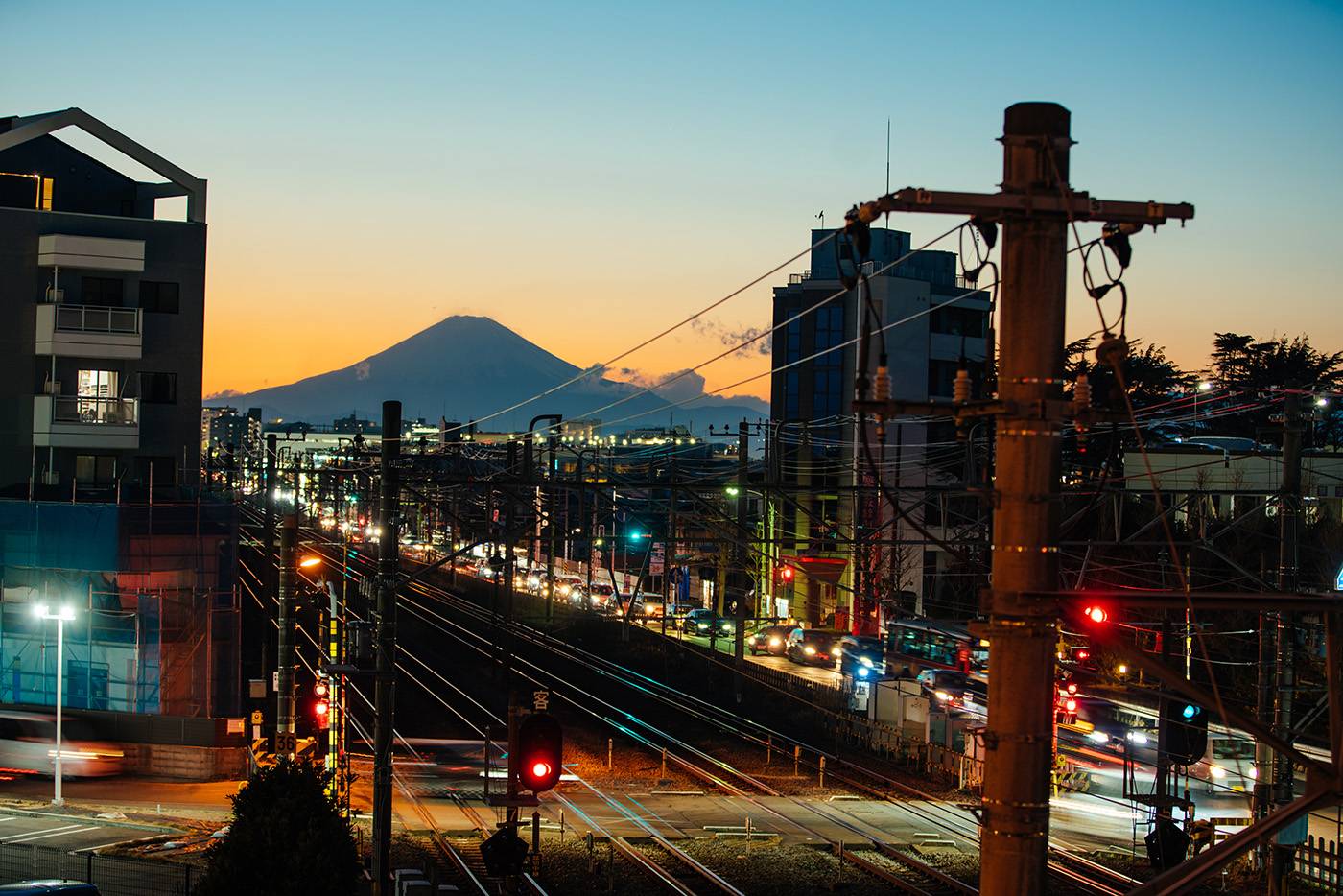 The picture of the railroad crossing with beautiful sunset sky and silhouette of Mt Fuji.