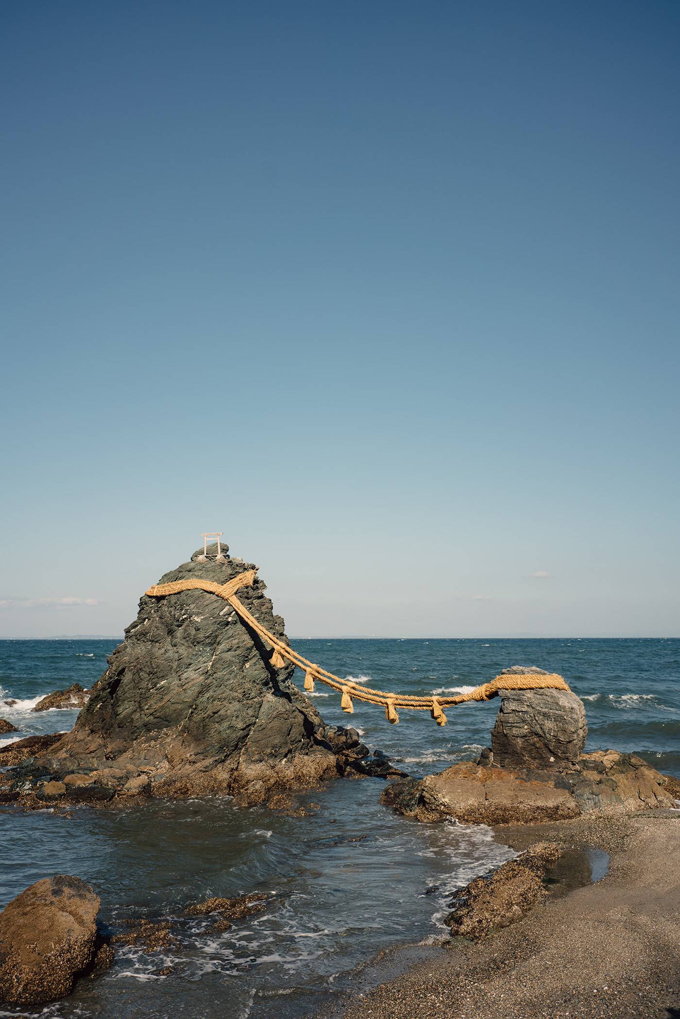 Scenic view of Wedded Rocks connected with shimenawa rope and located in sea under blue sky on sunny day in Japan
