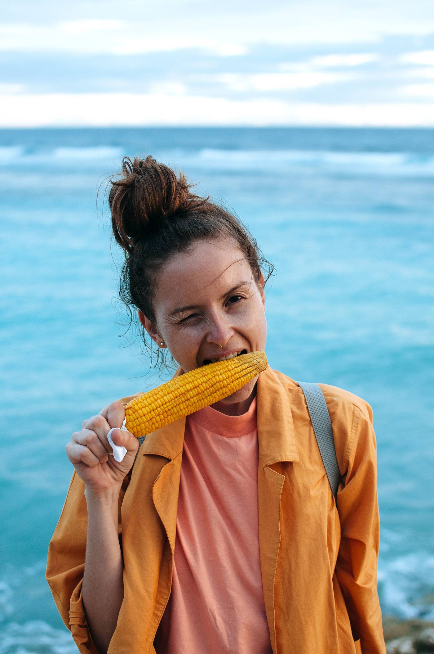Young Woman Enjoying Grilled Corn On The Ocean Background