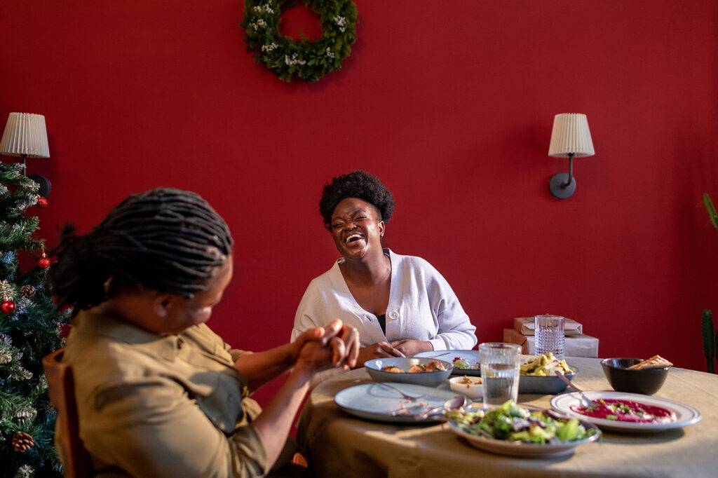Woman and her mother sitting at table at home and eating, celebrating Christmas together