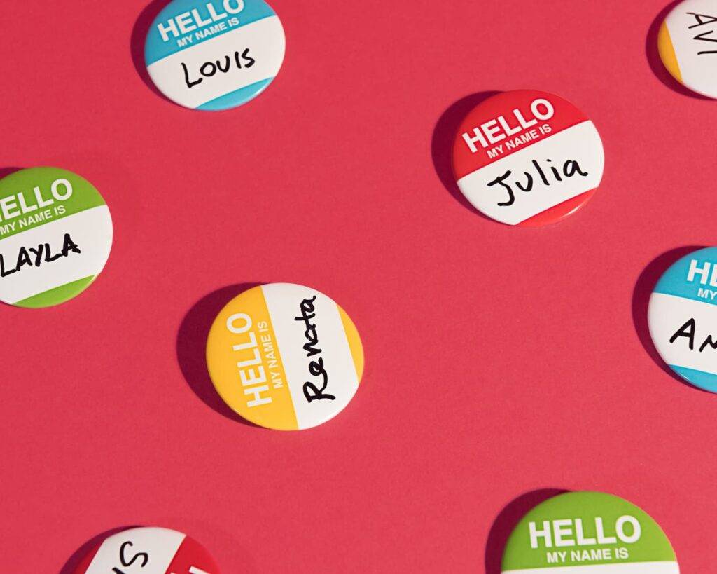 Several Hello my name Is button name tags on a red backdrop