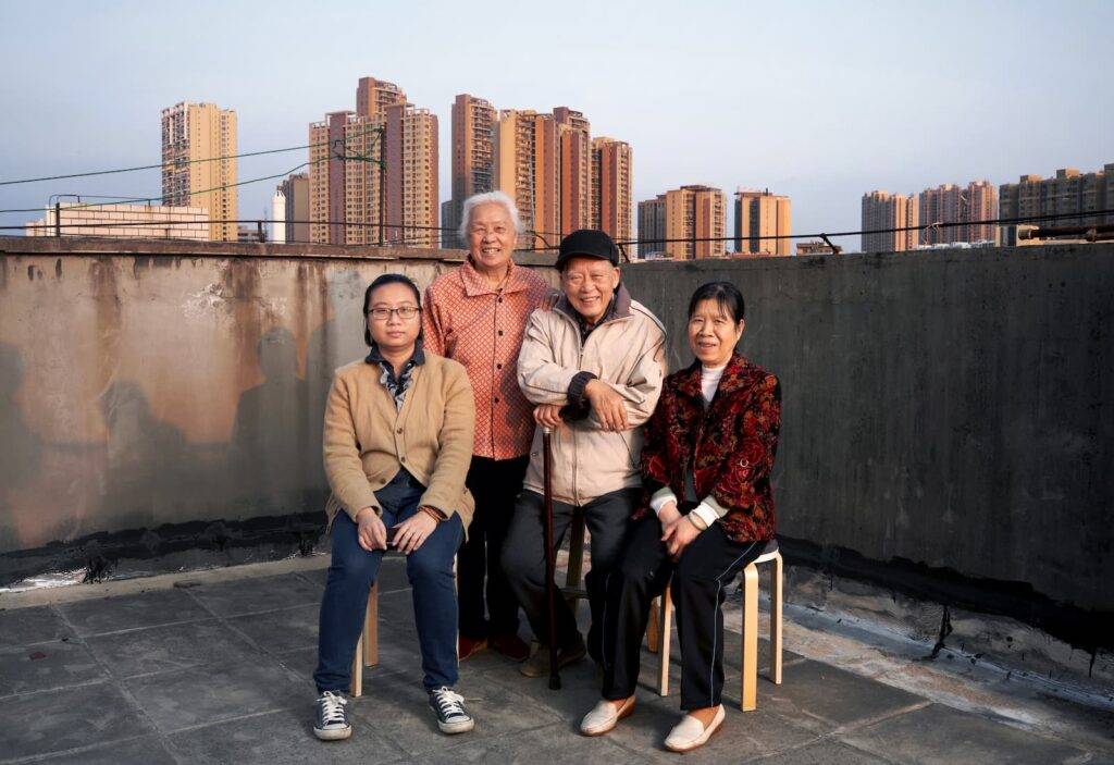 Group Photo Of Family Records Of Asian Chinese. On the roof of an old house with city buildings in the background