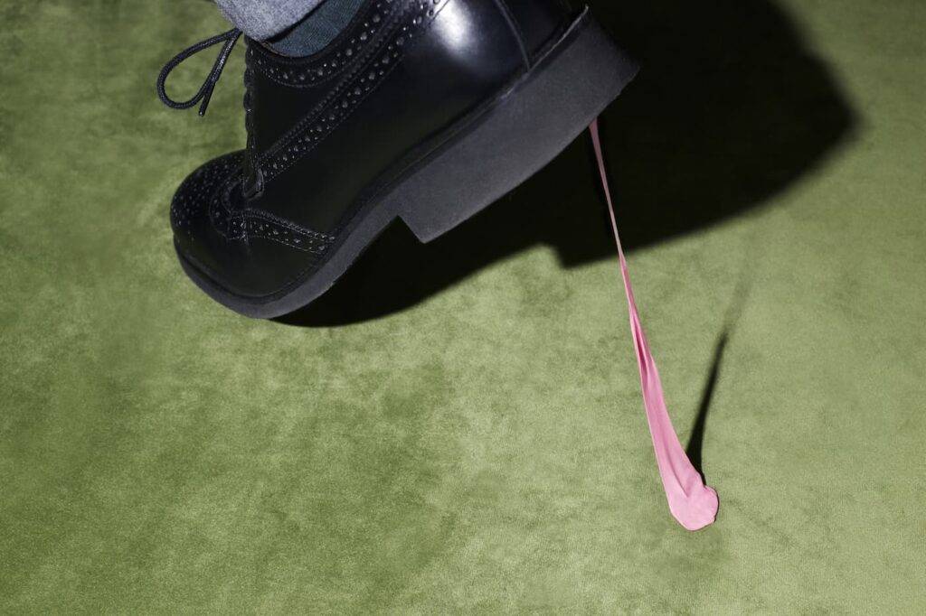 Man walking has chewing gum stuck to the sole of his shoe