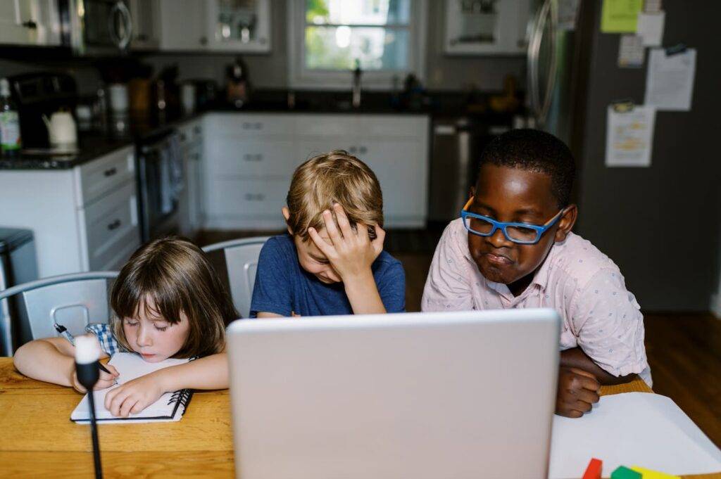 Three kids having fun at a computer photographed with diffused on camera flash