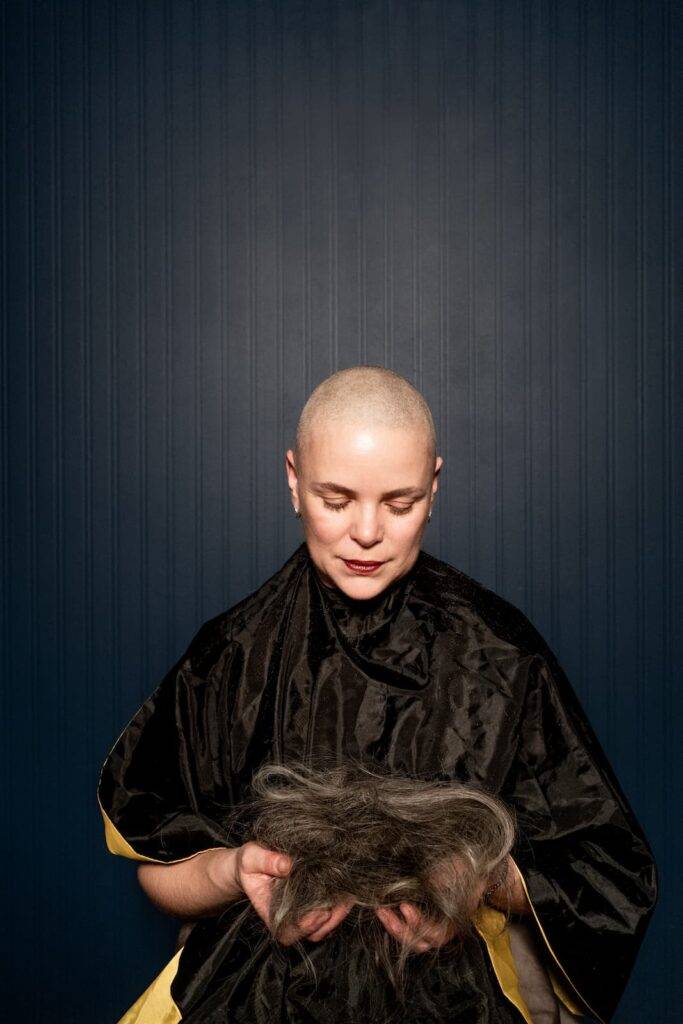 bald trimmed woman holding her hairs in hands