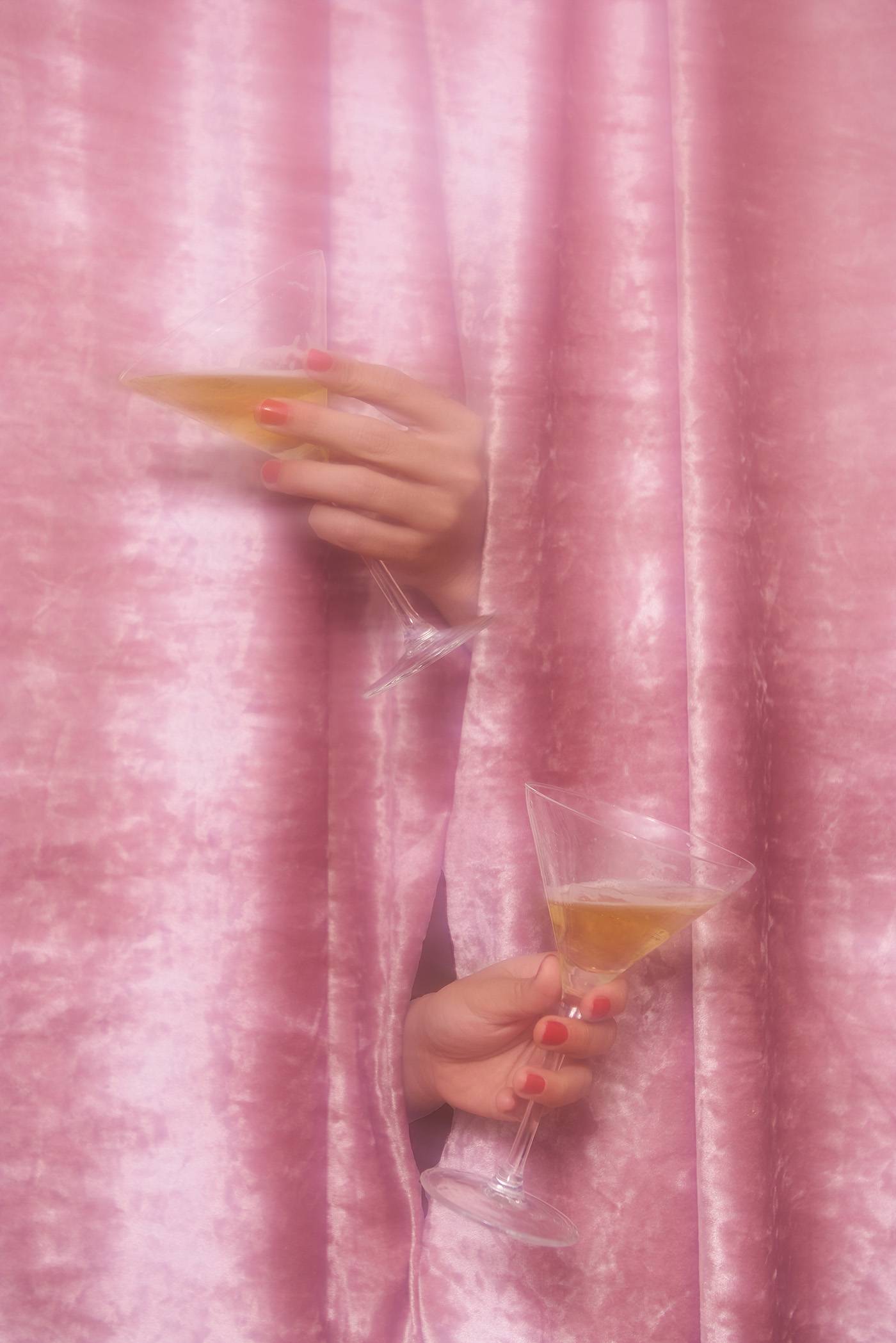 Dizzy photo of two glasses of champagne in a pink curtain