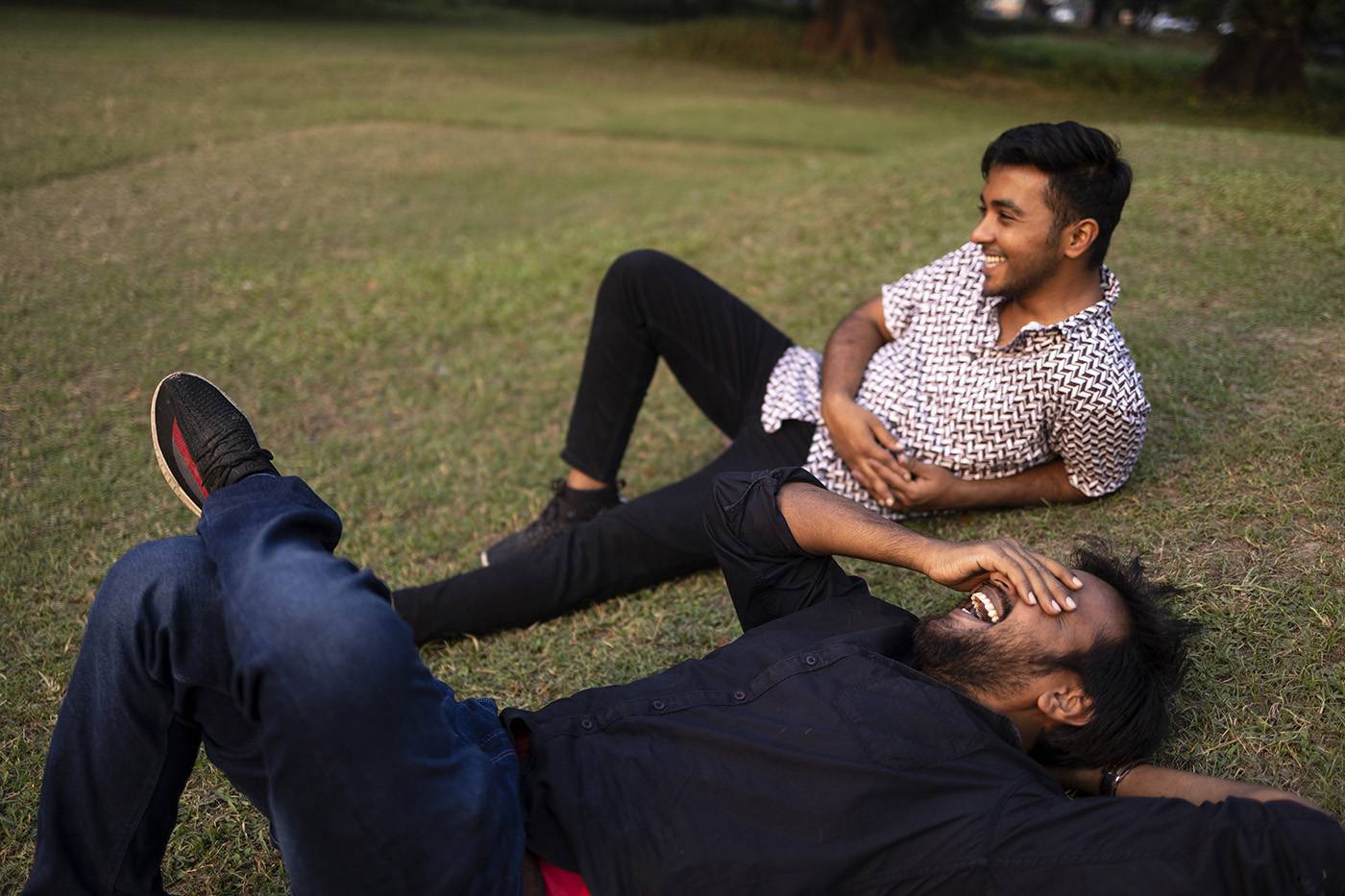 Two friends relaxing and interacting lying on grass ground at outdoors