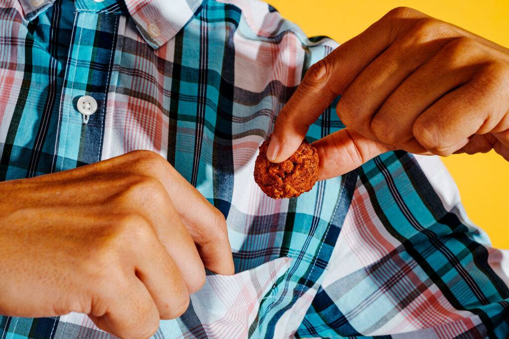 a young man is putting a veggie meatball in the pocket of his shirt