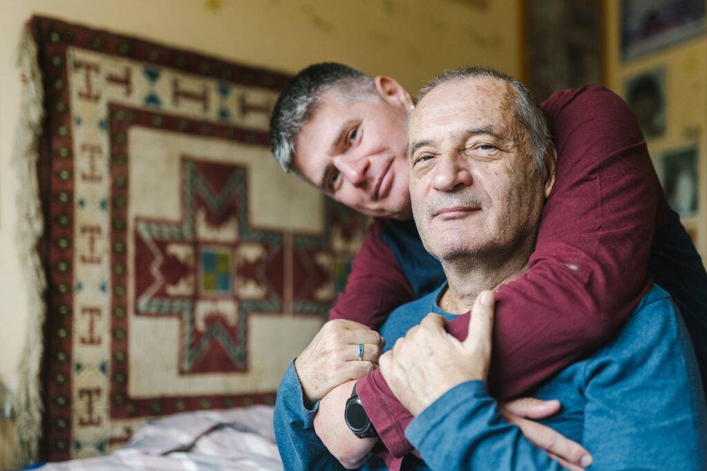 Gay Couple Hugging In Bed.