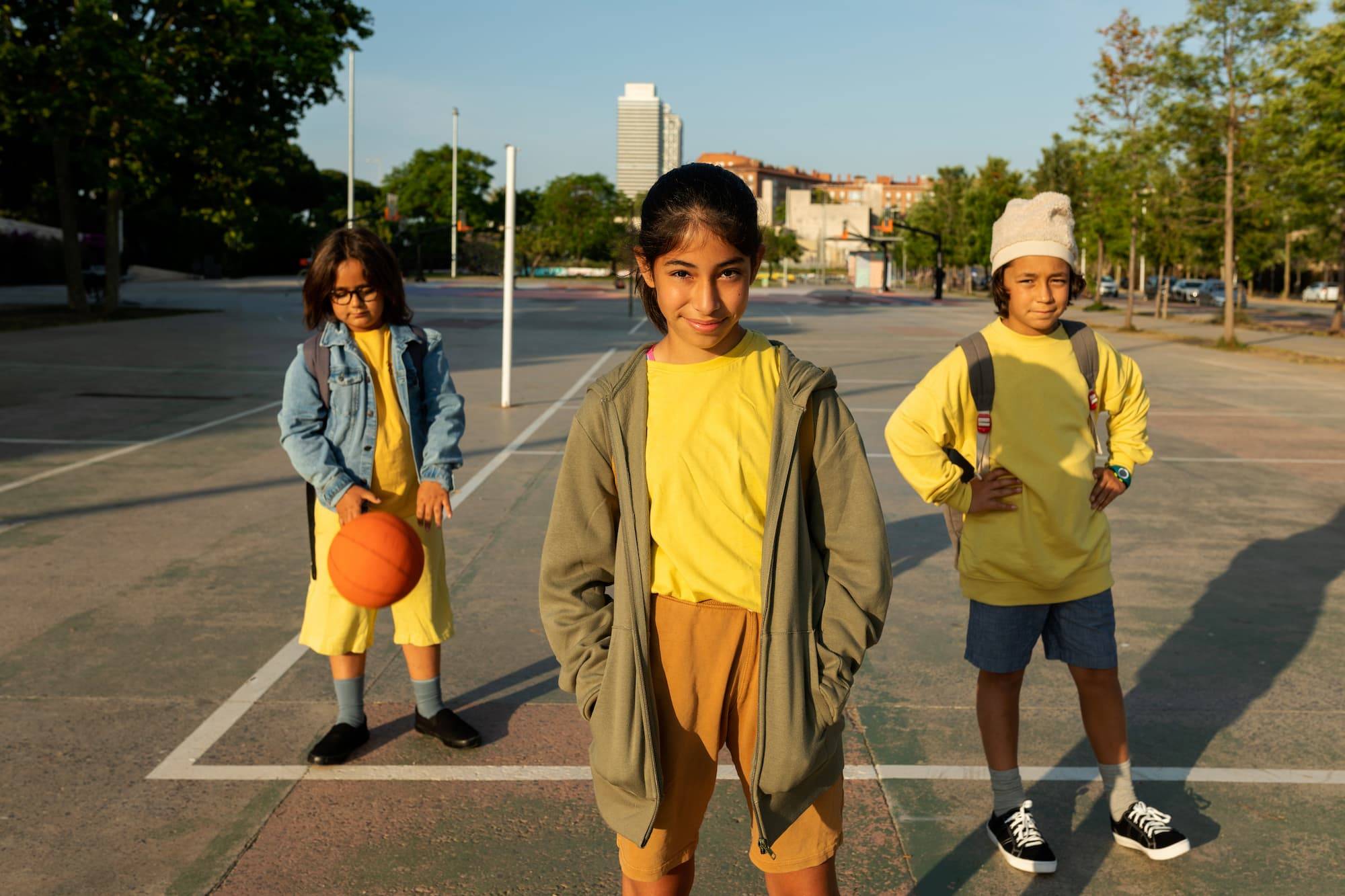 Portrait of cool classmates posing looking at camera after school wearing casual clothes and a basketball outdoor