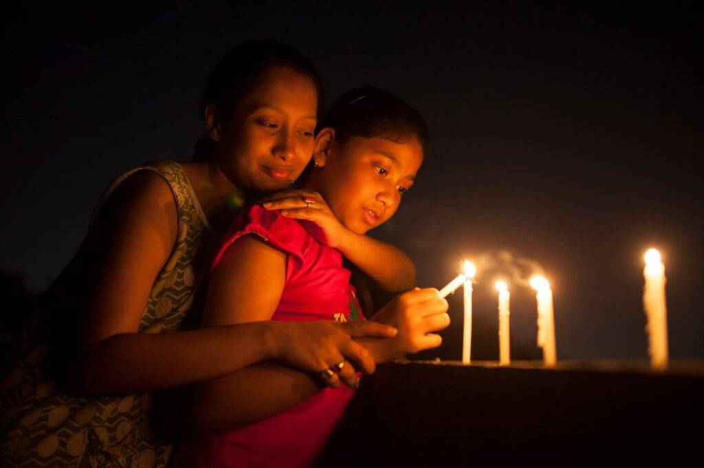 Teenage Girl And Young Woman Lighting Candle At Night In Outdoor
