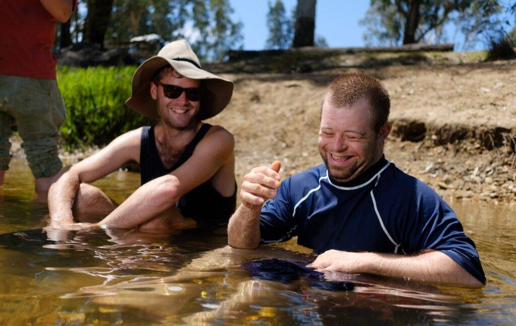 Two Men Sharing A Joke While Wading In River