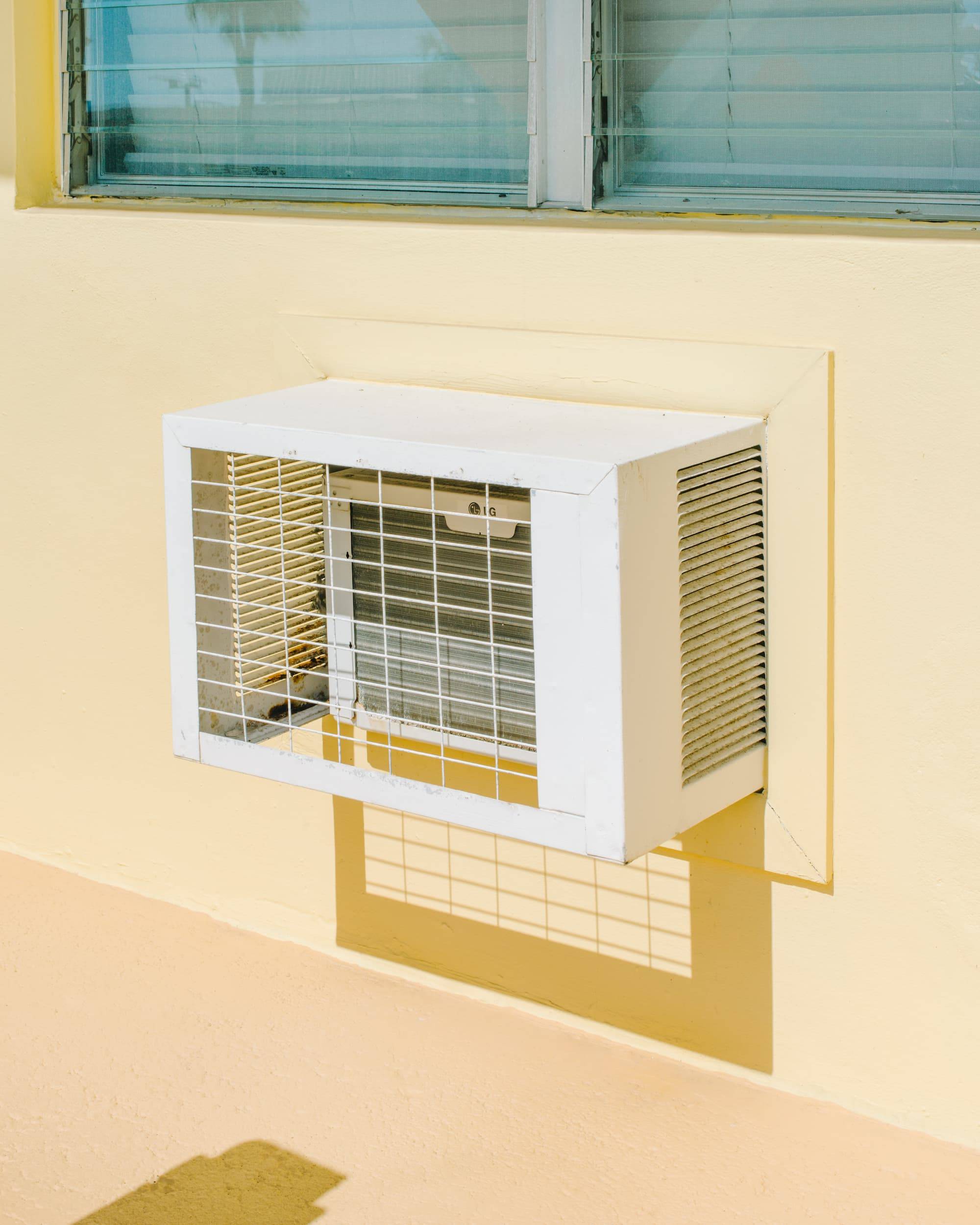 An old air conditioner on a yellow wall