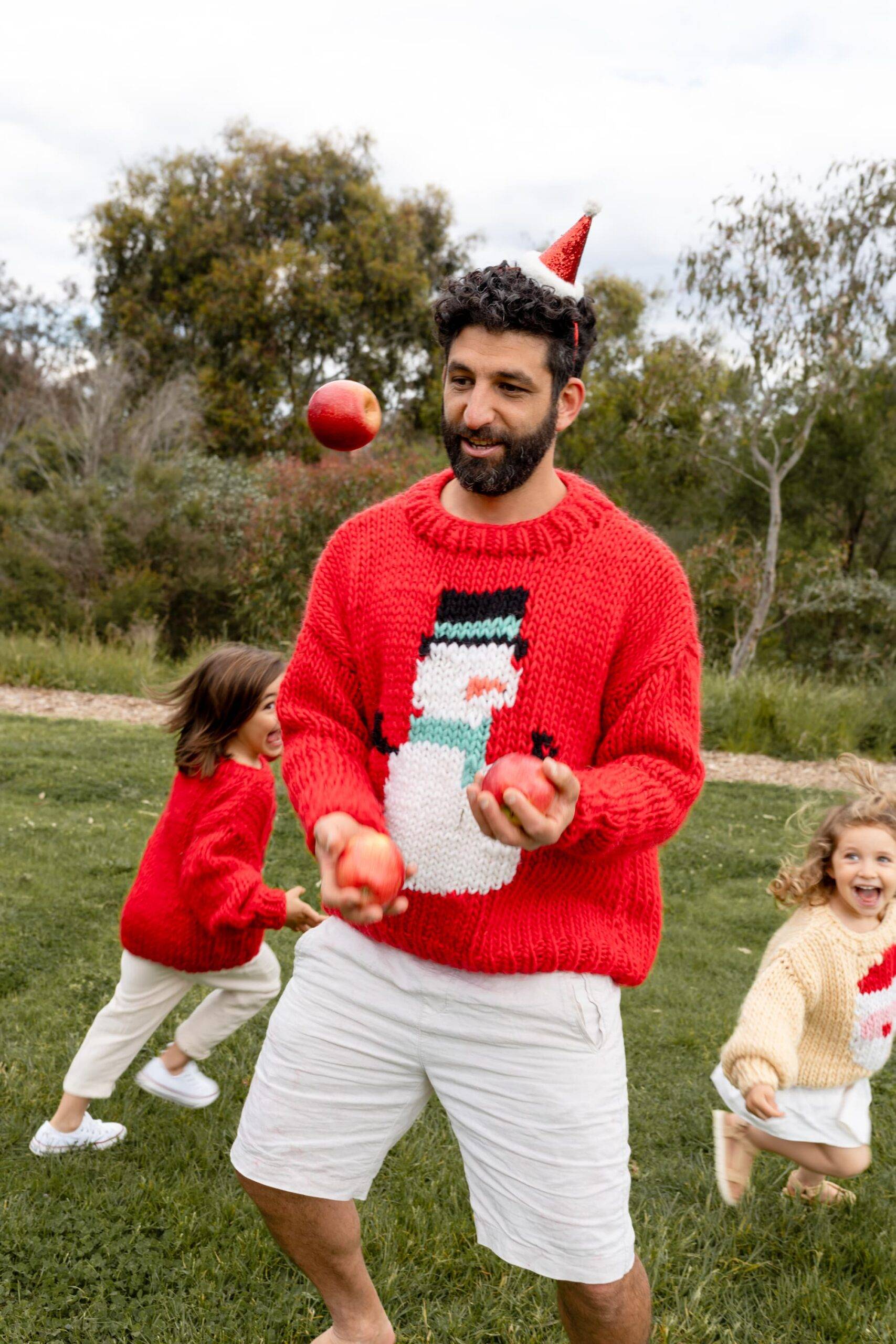 Dad with his kids in colourful Christmas knit enjoying some time together and playing outside.