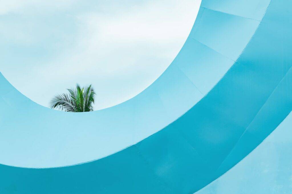 Blue circular construction framing a palm tree in a half circle with the turquoise sky in the background in Colima Mexico