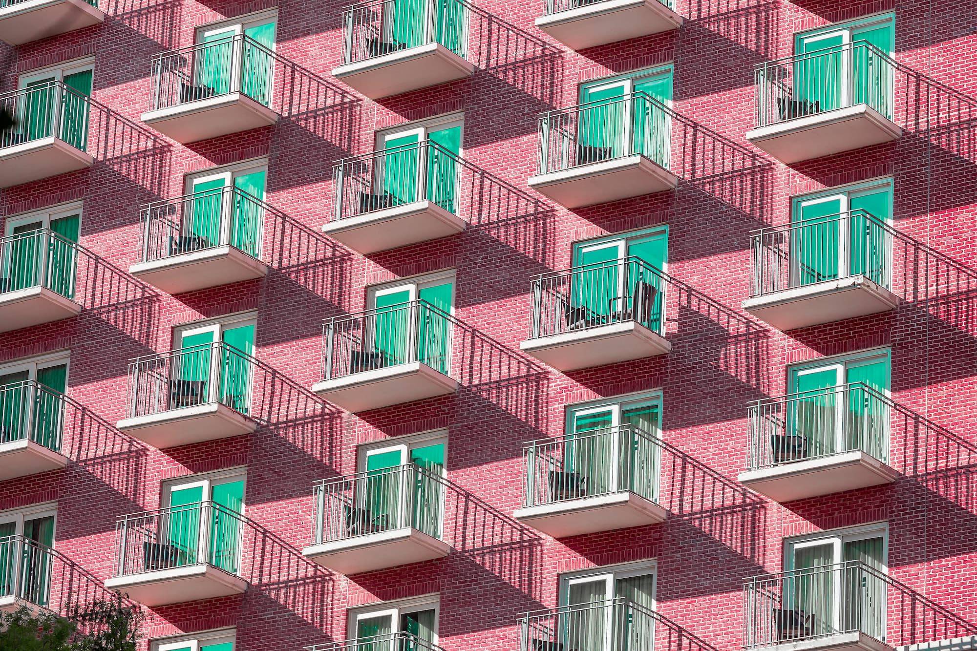 Pink hotel building with blue windows forming patterns and shadow in San Antonio Texas