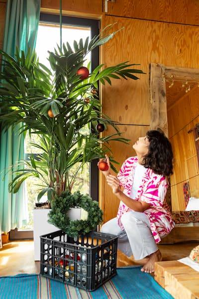Woman Decorating Potted Palm At Home