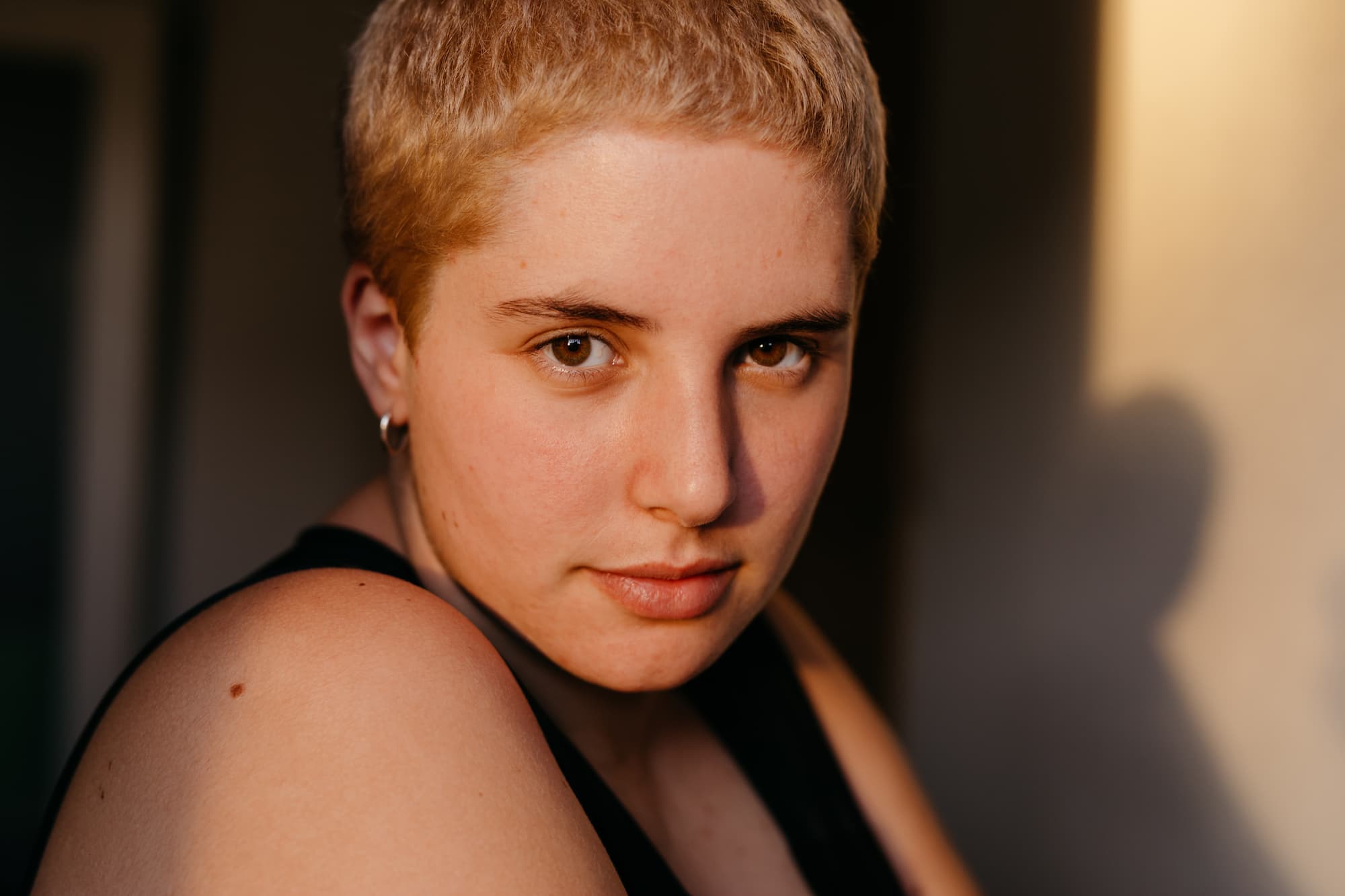 Portrait of crop young non binary person with brown eyes and breast binding looking at camera